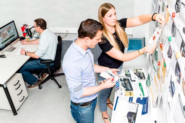Two persons are working out a marketing concept on a project wall